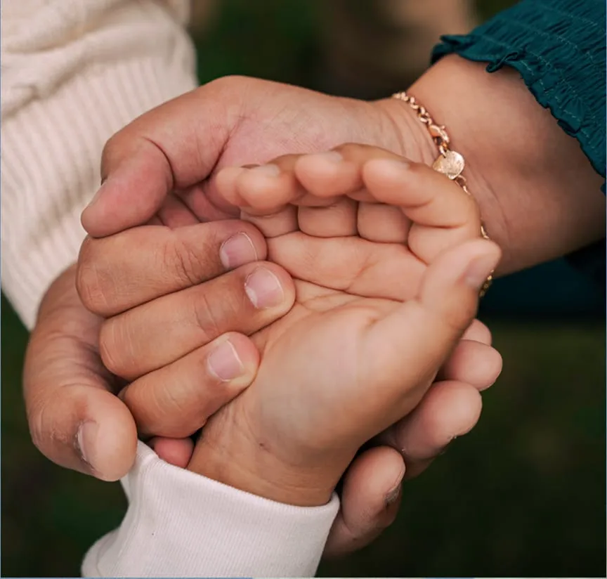 A photo of three generations of hands together to suggest wellbeing and support.